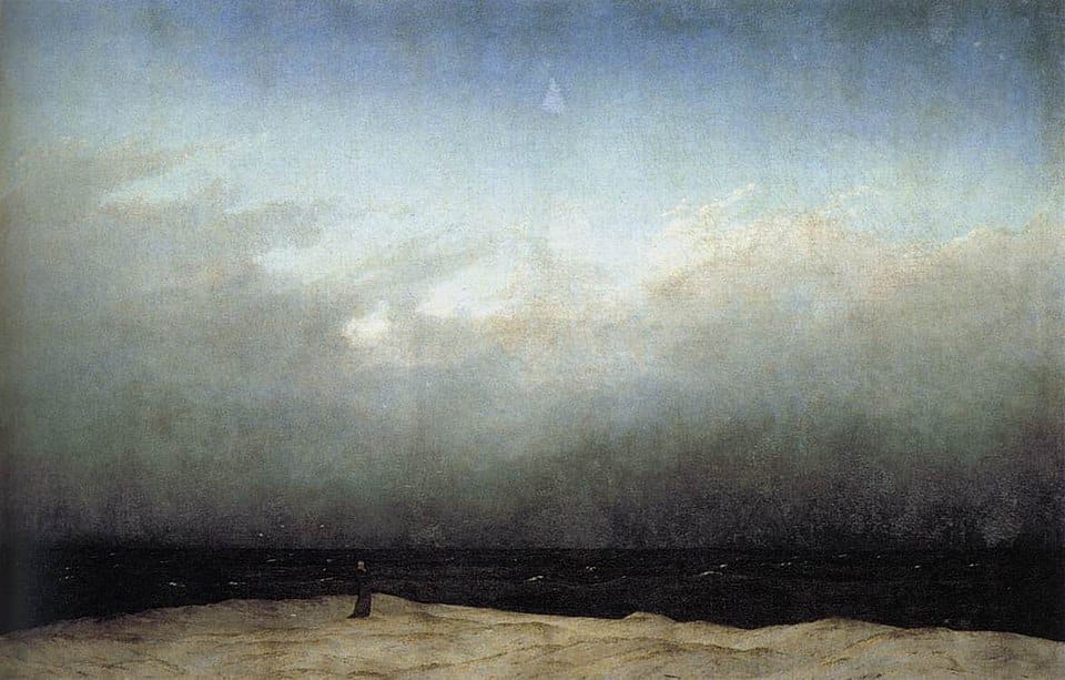 Caspar David Friedrich's oil painting (1809) depicting a tiny, solitary monk standing on a low, beige dune. He faces a vast, almost black sea and an immense, oppressive grey sky that dominates three-quarters of the canvas, emphasizing the scale of the void against the human figure.